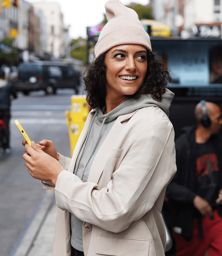 Woman holding a smartphone on a city street.